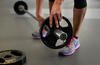 A beginner athlete in the newly offered tactical fitness class, OnRamp, adds a 10-pound weight to a barbell at Minot Air Force Base, N.D.