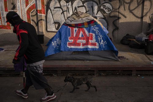 Man walks past a homeless encampment in Los Angeles