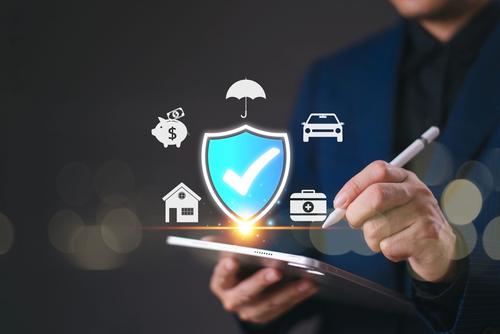 A hand holding a pen appears to be checking items on a list amid graphic icons representing forms of insurance.