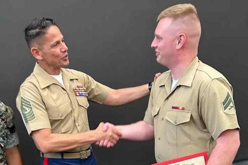 Sgt. Maj. of the Marine Corps Carlos Ruiz shakes Cpl. Andrew Hundley’s hand