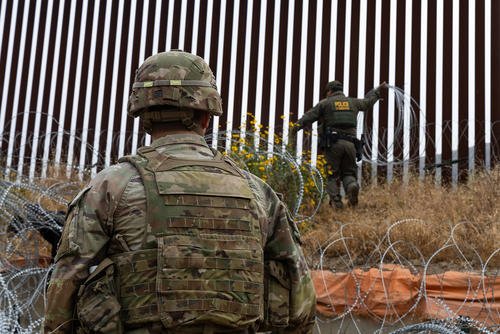 Customs and Border Protection agent places concertina wire along the border