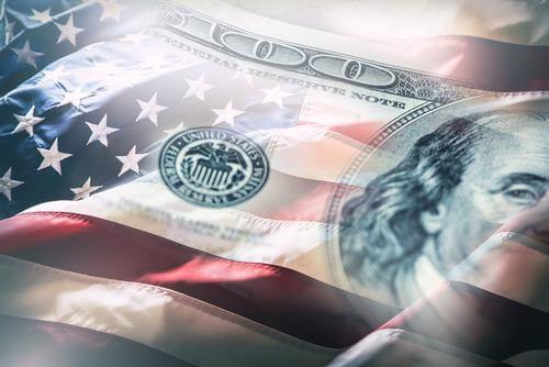 A US $100 bill and the US flag meld in a photo illustration.